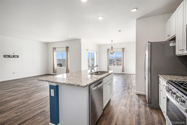 kitchen with light stone counters, stainless steel appliances, an island with sink, and white cabinets