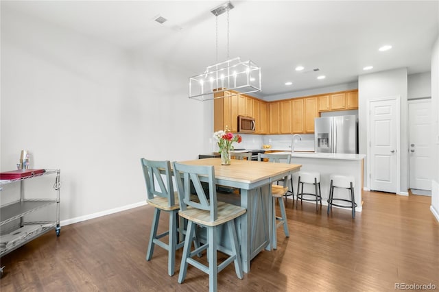 12973 Grant Cir E Unit A, Thornton, CO 80241 - kitchen with appliances with stainless steel finishes, light countertops, a chandelier, dark wood-type flooring, and a kitchen bar