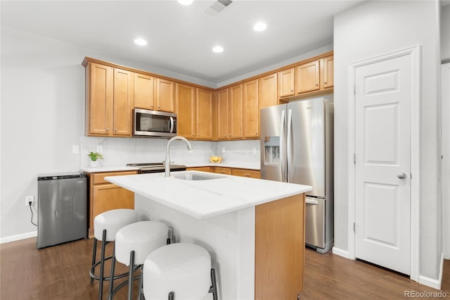 12973 Grant Cir E Unit A, Thornton, CO 80241 - kitchen with appliances with stainless steel finishes, dark wood-type flooring, a center island with sink, a breakfast bar, and recessed lighting