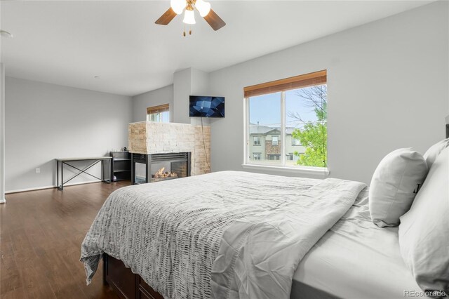 12973 Grant Cir E Unit A, Thornton, CO 80241 - bedroom with multiple windows, dark wood finished floors, a glass covered fireplace, and a ceiling fan