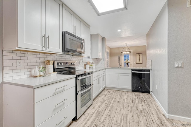 kitchen with light wood finished floors, black dishwasher, range with two ovens, backsplash, and a sink