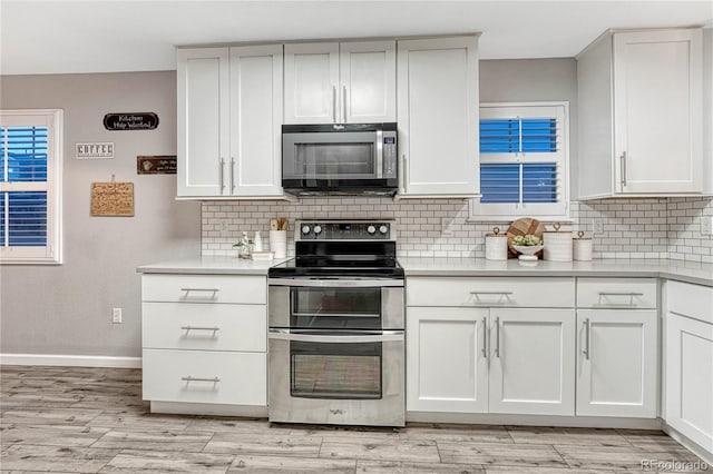 kitchen featuring light wood-style floors, appliances with stainless steel finishes, light countertops, and backsplash