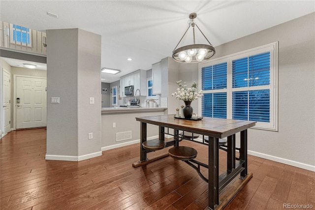 dining area with baseboards, visible vents, and hardwood / wood-style floors