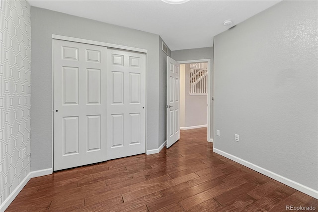 unfurnished bedroom featuring a closet, hardwood / wood-style flooring, and baseboards