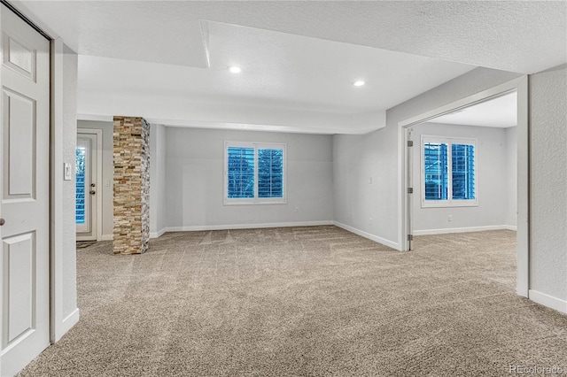 carpeted spare room with a textured ceiling, recessed lighting, decorative columns, and baseboards