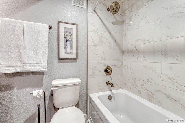 bathroom featuring toilet, bathtub / shower combination, visible vents, and a textured wall