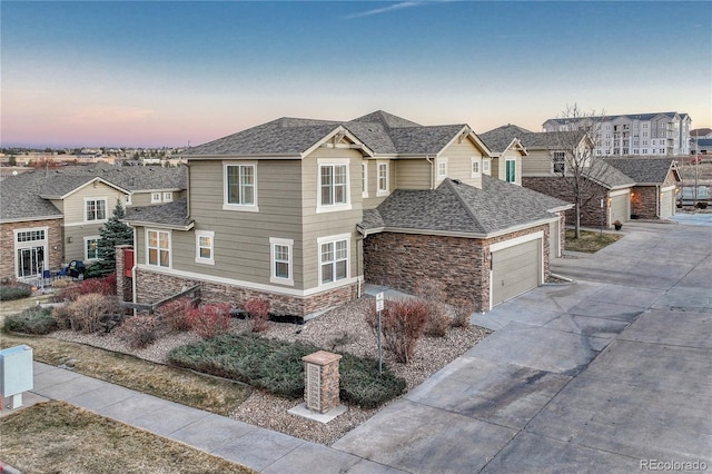 view of front of home featuring a shingled roof, stone siding, and concrete driveway