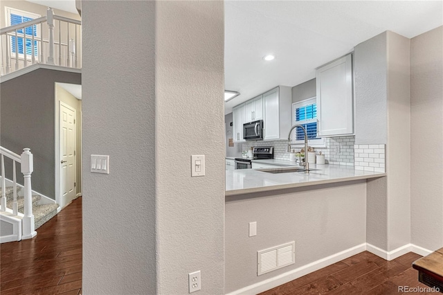 kitchen with visible vents, dark wood finished floors, a sink, stainless steel appliances, and backsplash