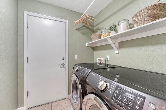 laundry area with laundry area, light tile patterned floors, separate washer and dryer, and a textured wall