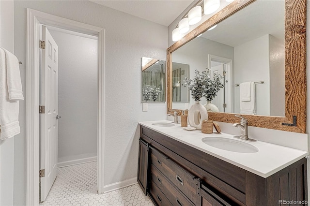 bathroom featuring tile patterned flooring, a sink, baseboards, and double vanity