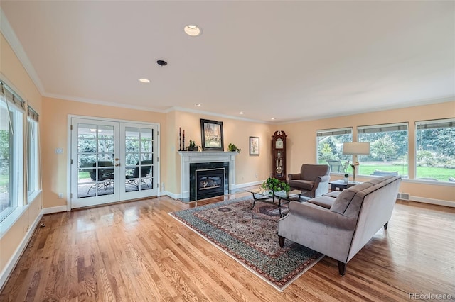 living room with a wealth of natural light, ornamental molding, and light wood-type flooring