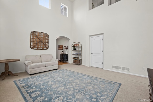 carpeted living room featuring a towering ceiling