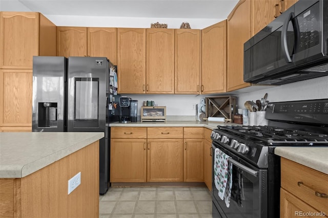 kitchen with stainless steel refrigerator with ice dispenser and black gas range