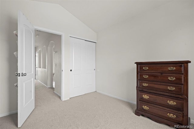 unfurnished bedroom with light carpet, a closet, and vaulted ceiling