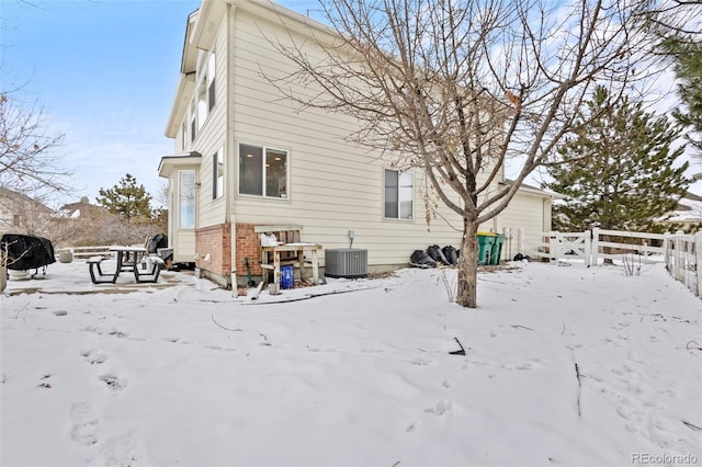 snow covered rear of property with central AC unit