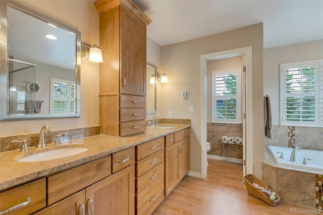 2359 Indian Paintbrush Cir, Highlands Ranch, CO 80129 - bathroom with double vanity, toilet, a bath, wood finished floors, and baseboards