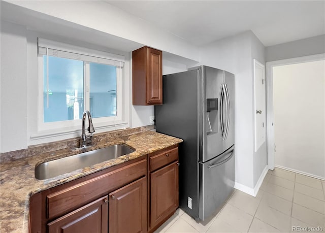 828 Mariposa St, Denver, CO 80204 - kitchen featuring stainless steel refrigerator with ice dispenser, a sink, dark stone countertops, light tile patterned floors, and baseboards
