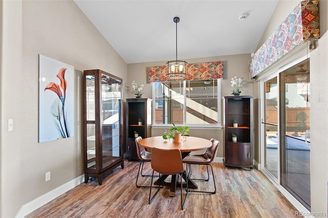 dining area featuring a notable chandelier, vaulted ceiling, and hardwood / wood-style floors