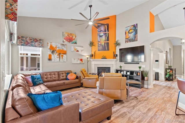 living room with ceiling fan, light hardwood / wood-style flooring, and high vaulted ceiling