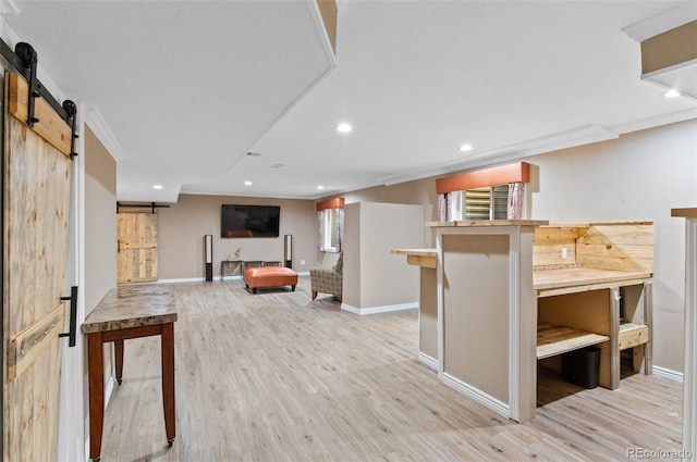 interior space with crown molding, light hardwood / wood-style flooring, a barn door, and a kitchen breakfast bar