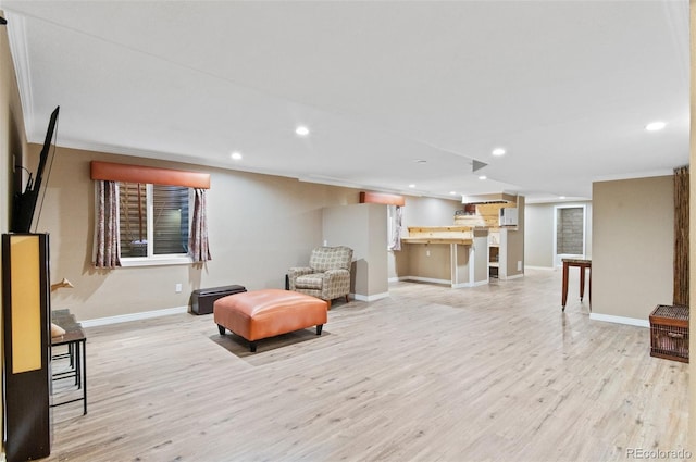 living area featuring crown molding and light hardwood / wood-style flooring