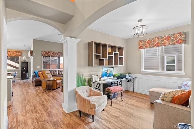 interior space featuring ornate columns, a chandelier, and light hardwood / wood-style flooring