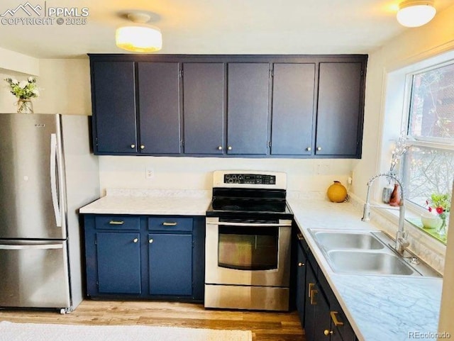 kitchen with blue cabinetry, appliances with stainless steel finishes, light hardwood / wood-style floors, and sink