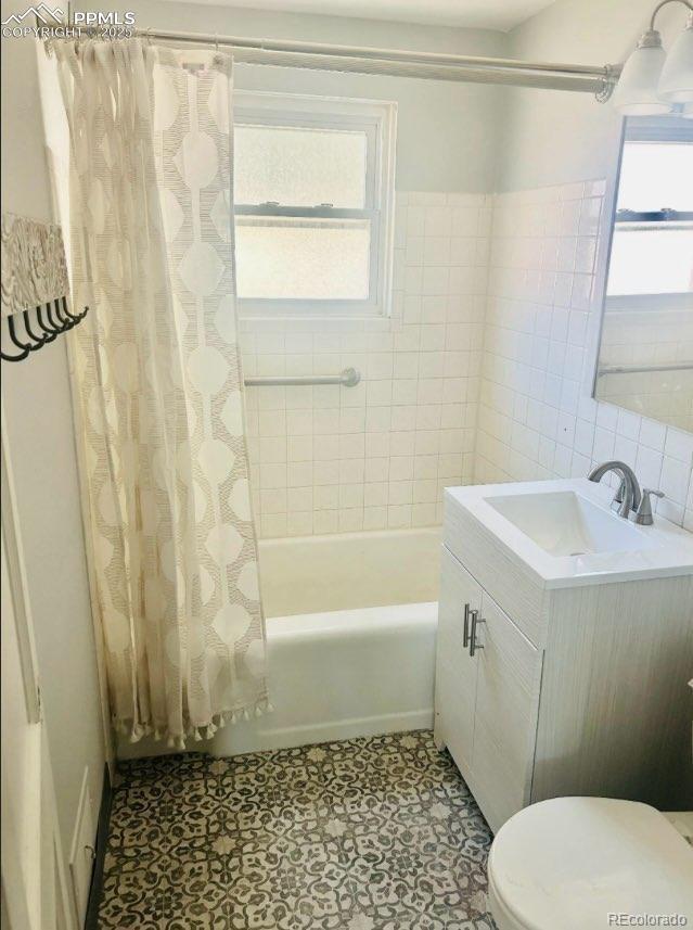 full bathroom featuring shower / bath combination with curtain, vanity, tile walls, and a wealth of natural light