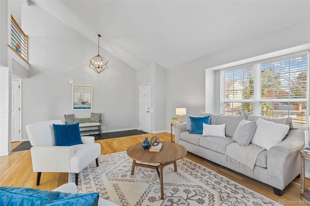 living room featuring an inviting chandelier, wood-type flooring, and high vaulted ceiling