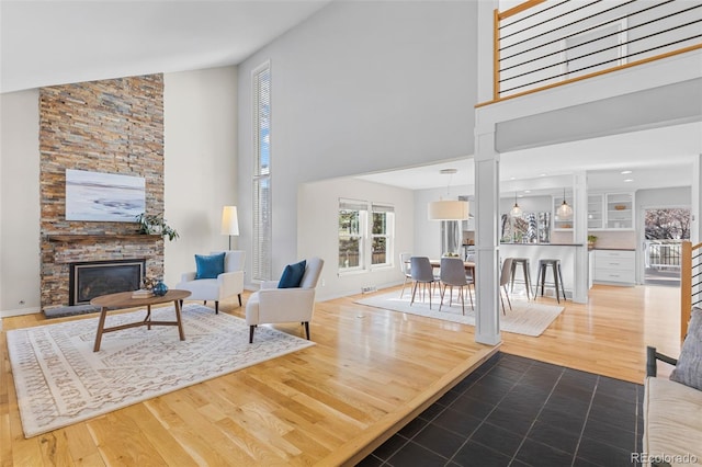 living room with hardwood / wood-style flooring, a fireplace, and a high ceiling