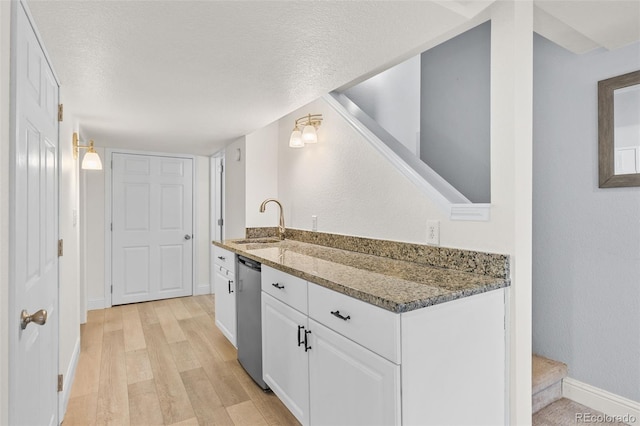 kitchen featuring white cabinetry, dishwasher, sink, dark stone counters, and light wood-type flooring