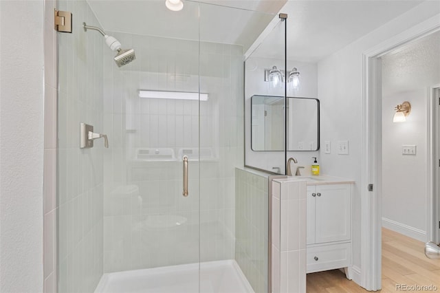 bathroom featuring an enclosed shower, vanity, and hardwood / wood-style flooring