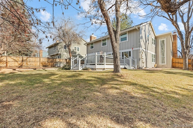 back of property featuring a wooden deck and a yard