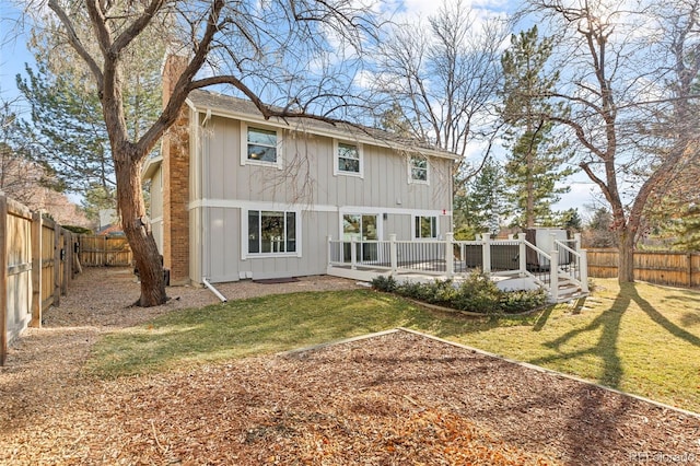 back of property with a wooden deck and a yard