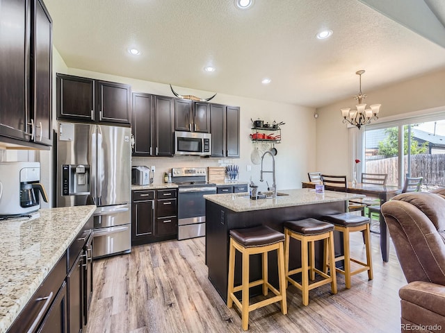 1936 Traildust Dr, Milliken, CO 80543 - kitchen featuring appliances with stainless steel finishes, a sink, a kitchen bar, a chandelier, and light wood-style flooring
