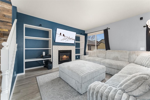 living area with a tiled fireplace, baseboards, and wood finished floors