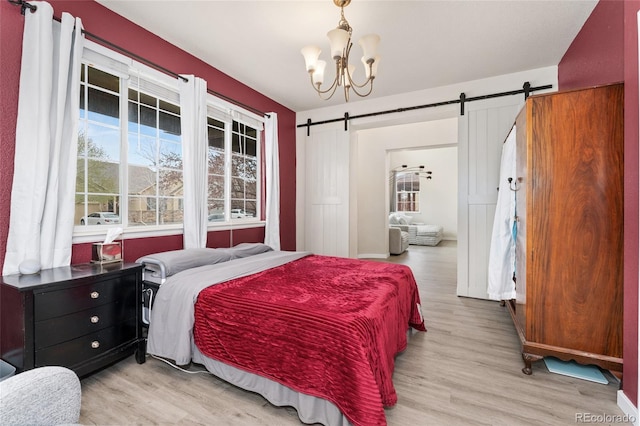 bedroom featuring a chandelier, light wood finished floors, and a barn door