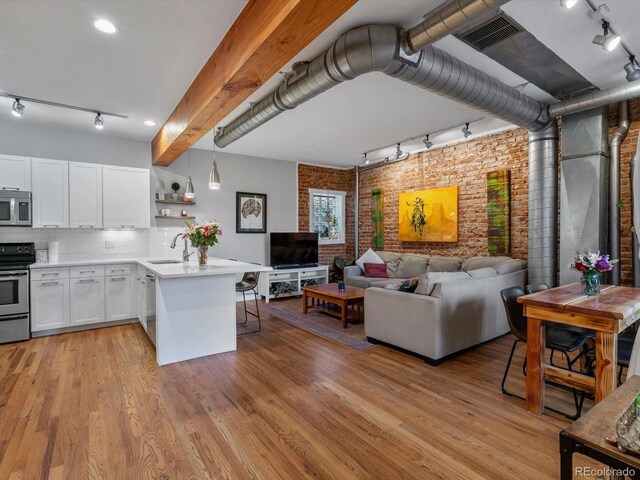 2524 Champa St Unit 1, Denver, CO 80205 - living room with rail lighting, brick wall, and light wood-style floors