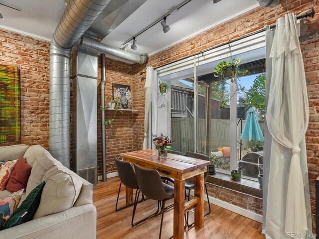 2524 Champa St Unit 1, Denver, CO 80205 - dining space featuring brick wall, light wood-type flooring, and track lighting