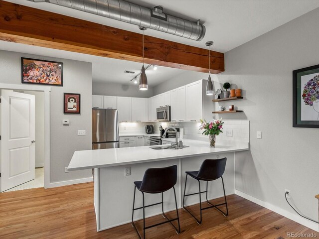 2524 Champa St Unit 1, Denver, CO 80205 - kitchen with appliances with stainless steel finishes, a peninsula, backsplash, a breakfast bar, and light countertops