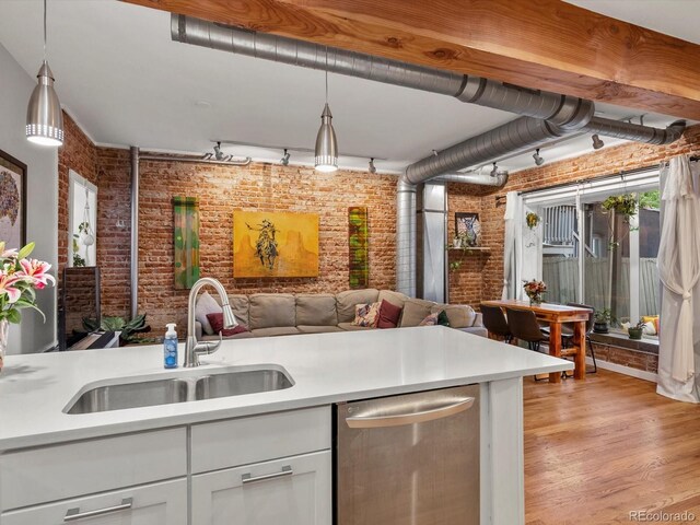 2524 Champa St Unit 1, Denver, CO 80205 - kitchen with brick wall, stainless steel dishwasher, a sink, open floor plan, and light countertops