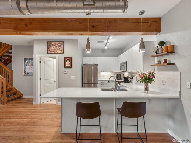 2524 Champa St Unit 1, Denver, CO 80205 - kitchen featuring appliances with stainless steel finishes, a peninsula, a sink, light countertops, and light wood-style floors
