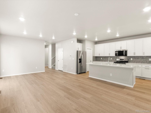 kitchen featuring stainless steel appliances, sink, a center island with sink, and white cabinets