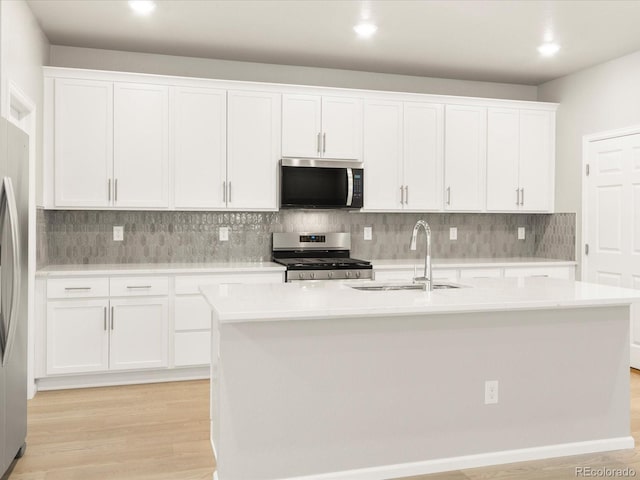 kitchen featuring sink, tasteful backsplash, appliances with stainless steel finishes, a kitchen island with sink, and white cabinets