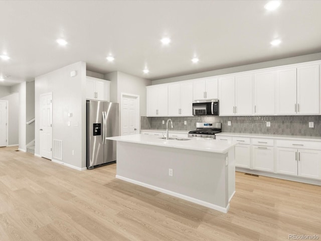 kitchen with a kitchen island with sink, sink, white cabinetry, and stainless steel appliances