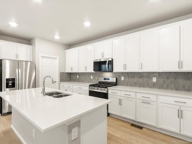 kitchen featuring an island with sink, appliances with stainless steel finishes, sink, and white cabinets