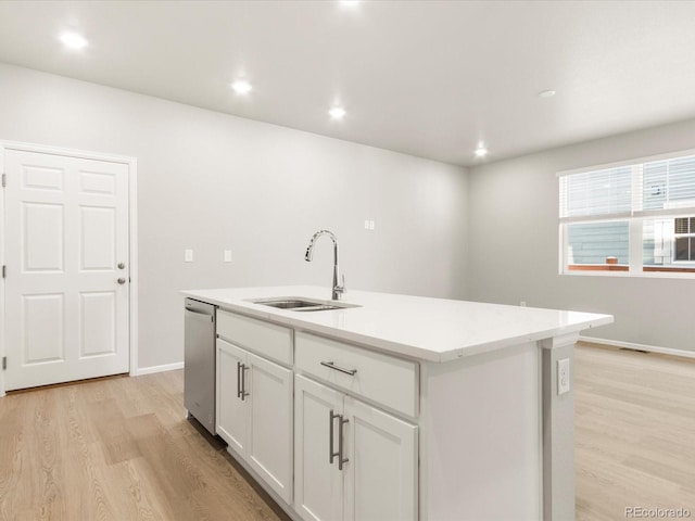 kitchen featuring sink, dishwasher, white cabinetry, an island with sink, and light wood-type flooring