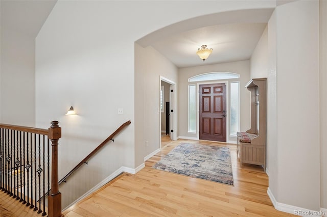 entrance foyer featuring light wood-style flooring, arched walkways, and baseboards
