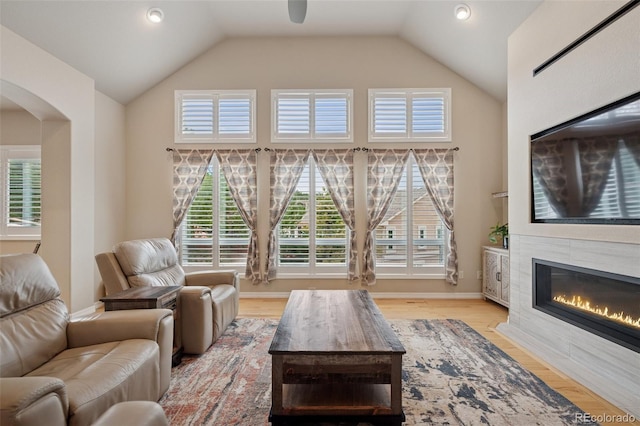 living room featuring a fireplace, high vaulted ceiling, arched walkways, wood finished floors, and recessed lighting
