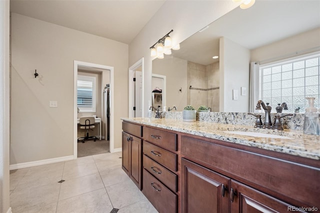 bathroom with a stall shower, double vanity, healthy amount of natural light, and baseboards